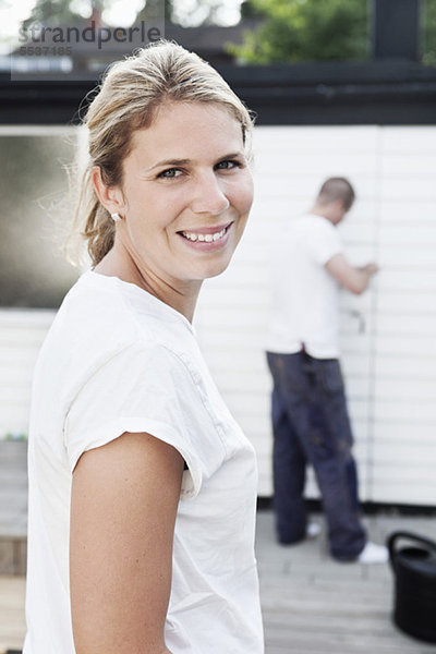 Porträt einer lächelnden Frau mit Mann im Hintergrund
