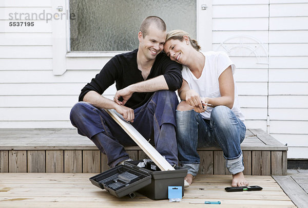 Frau  die sich auf die Schulter des Mannes stützt  während sie ihr Haus renoviert.