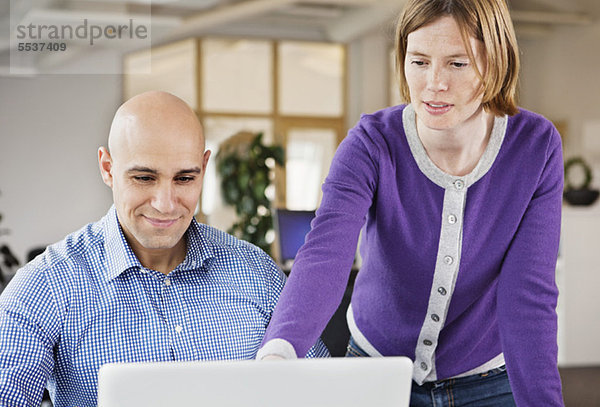 Weibliche Führungskraft  die auf den Laptop zeigt  mit einem Mann  der auf den anderen schaut.