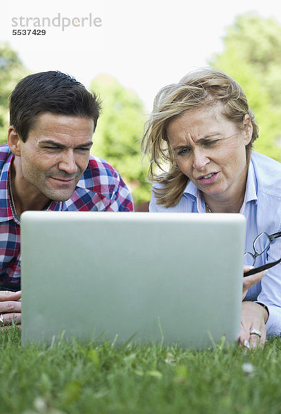 Geschäftsmann und Geschäftsfrau mit Laptop im Gras