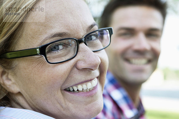Nahaufnahme einer glücklichen Frau in Brille mit Mann im Hintergrund
