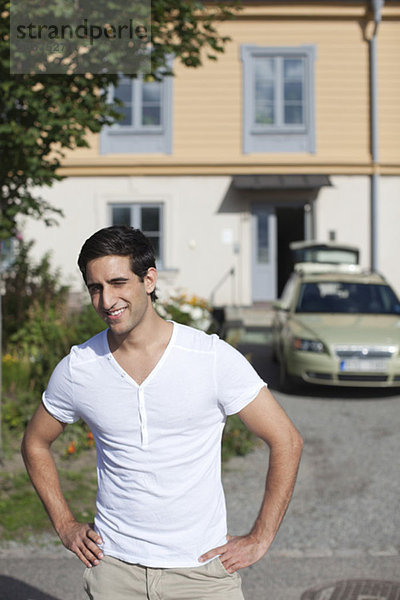 Frontansicht des jungen Mannes mit Auto im Hintergrund