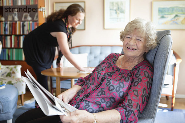 Porträt einer lächelnden Seniorin mit einer mittleren erwachsenen Frau im Hintergrund