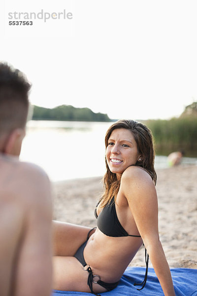 Schöne junge Frau im Bikini  die den Mann am Strand ansieht.