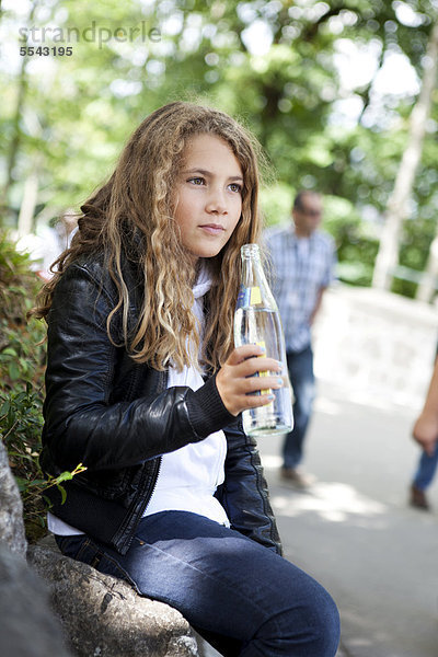 Mädchen mit Mineralwasser in einer Glasflasche  beim Ausruhen