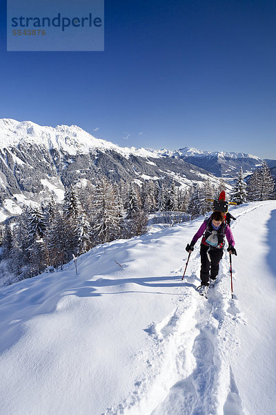 Schneeschuhgeher beim Aufstieg zur Jagelealm im Ridnauntal oberhalb von Entholz  hinten das Ridnauntal und der Rosskopf  Südtirol  Italien  Europa