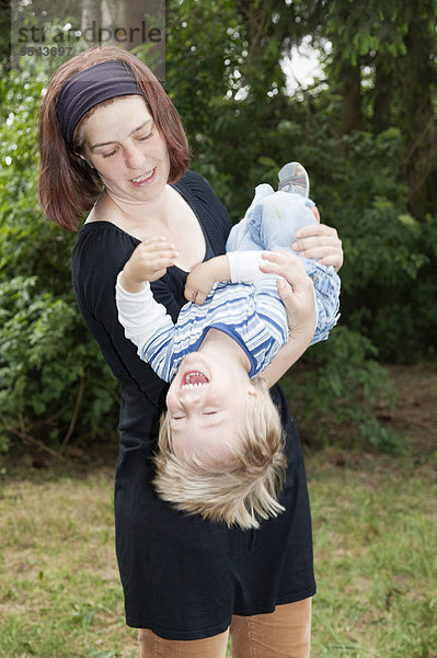 Mutter wirbelt ihren zweijährigen Sohn durch die Luft