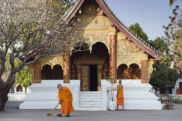 Mönche kehren am Morgen den Tempel  Wat Sibounheuang  Luang Prabang  UNESCO-Weltkulturerbe  Laos  Indochina  Asien