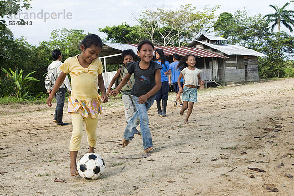 Schulkinder spielen Fußball auf dem Schulhof bevor der Unterricht beginnt  in einem Dorf ohne Straßenverbindung im Regenwald des Oriente  Curaray  Ecuador  Südamerika