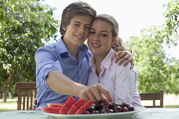 Junges Paar isst Obst im Freien