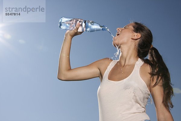 Junge Frau trinkt Wasser aus einer Flasche im Freien