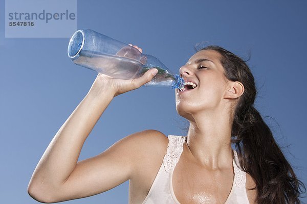 Junge Frau trinkt Wasser aus einer Flasche im Freien