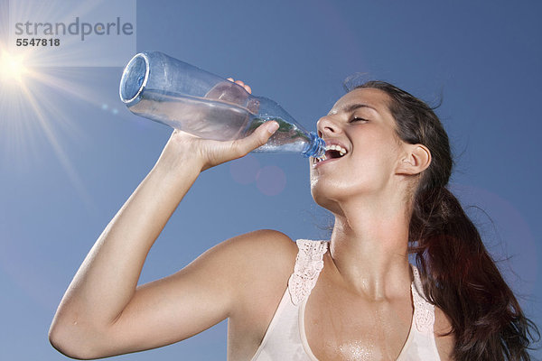 Junge Frau trinkt Wasser aus einer Flasche im Freien