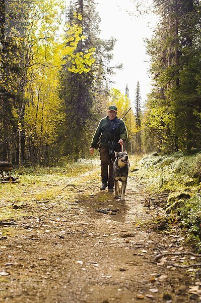 Mann mit Hund im Wald spazieren