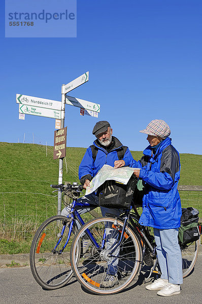 Fahrradfahrer  Radfahrer lesen Landkarte  Radweg am Deich bei Nesse  Ostfriesland  Niedersachsen  Deutschland  Europa