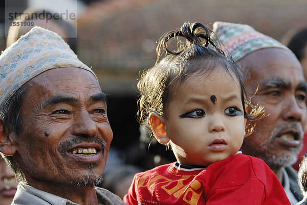 Männer mit traditioneller Kopfbedeckung und Kind beobachten Prozession  Taumadhi-Platz  Bhaktapur  Kathmandu-Tal  Nepal  Asien