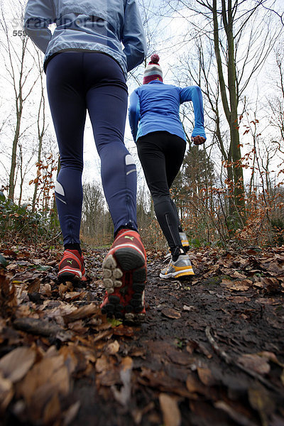 Zwei junge Frauen laufen im Winter im Wald  mit wind- und wasserdichter Funktionsbekleidung