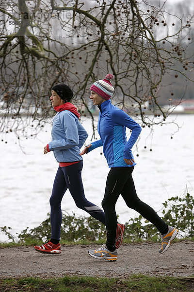 Zwei junge Frauen joggen im Winter  mit wind- und wasserdichter Funktionsbekleidung