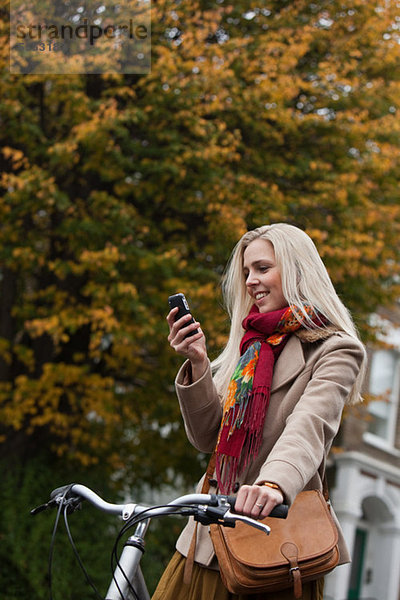 Junge Frau mit Fahrrad  Blick auf Handy