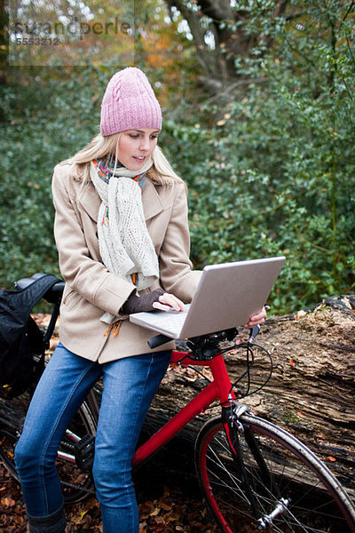 Frau im Freien mit Laptop und Fahrrad