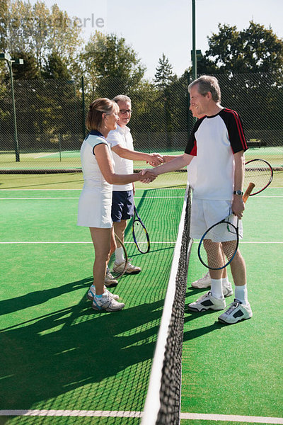 Leitende und ältere Erwachsene Händeschütteln auf Tennisplatz