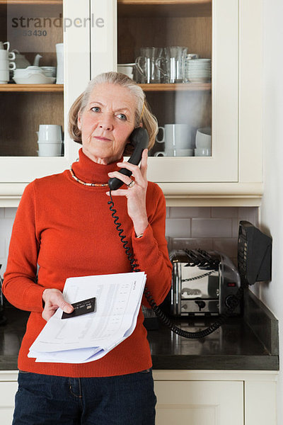 Seniorin am Telefon mit Auszug und Kreditkarte