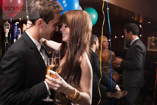 Zärtliches junges Paar auf der Party mit Champagner