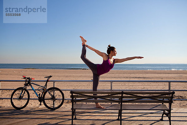 Frau in Yoga-Pose auf der Promenade