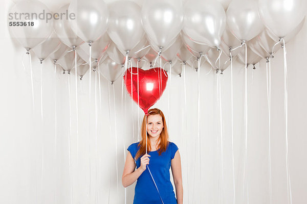 Young Woman holding Herz geformt Ballon