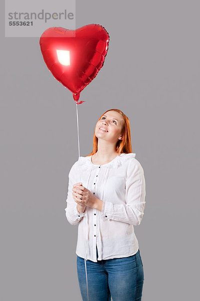 Young Woman holding Herz geformt Ballon