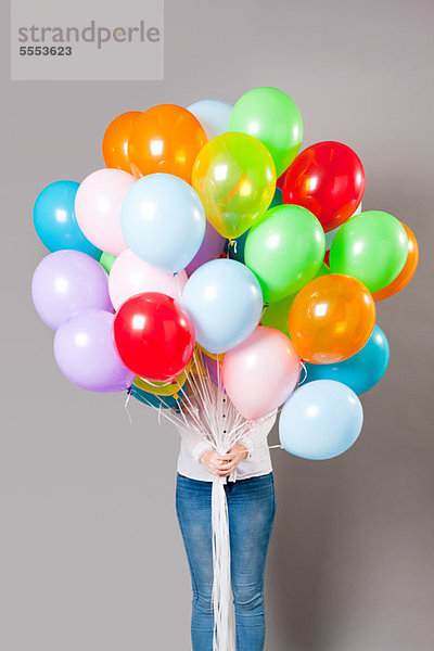 Frau hält eine große Menge an Luftballons