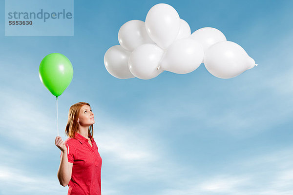 Young Woman looking at Wolke hergestellt aus Ballons