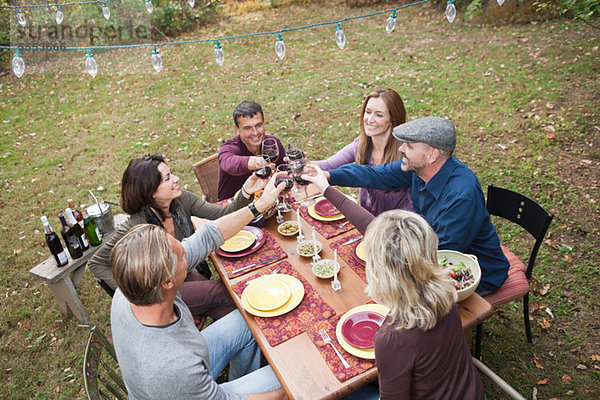 Freunde stoßen beim Abendessen im Freien an.