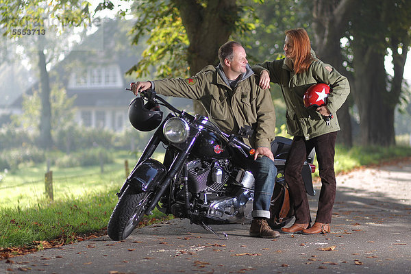 Paar an einem Motorrad auf einer Landstraße
