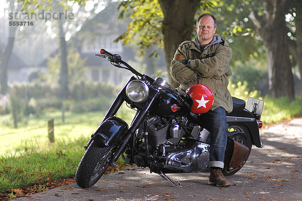 Mann sitzt auf einem Motorrad auf einer Landstraße