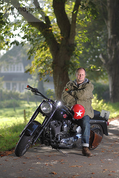 Mann sitzt auf einem Motorrad auf einer Landstraße