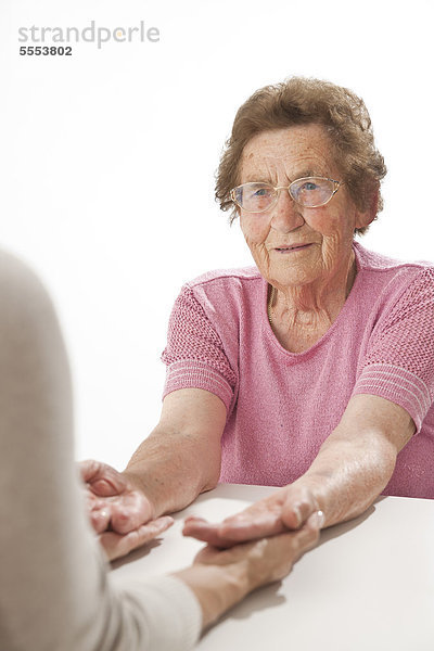 Reife Frau hält die Hände einer alten Frau