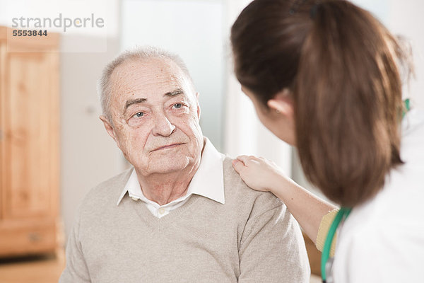 Ärztin legt Senior die Hand auf die Schulter