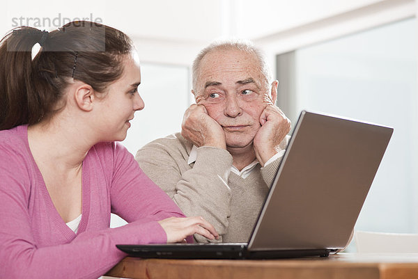 Junge Frau und frustrierter Senior am Laptop