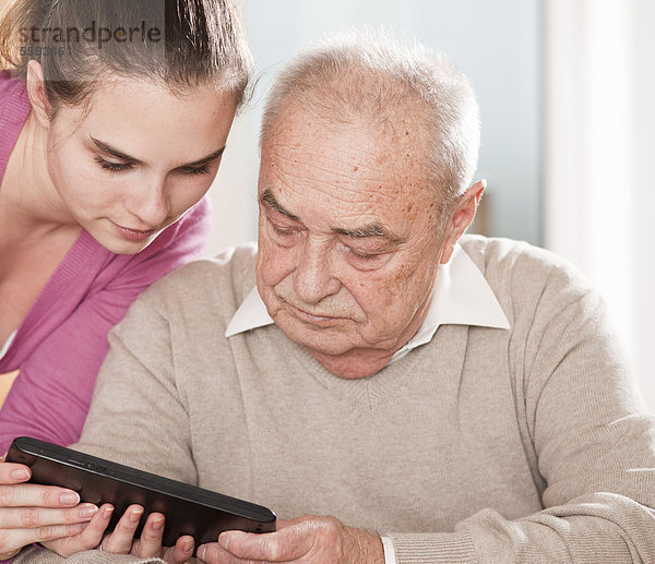 Junge Frau und Senior mit einem Tablet-PC