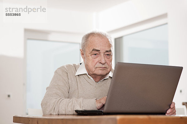 Senior benutzt Laptop am Tisch