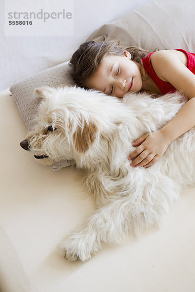 Mädchen entspannt mit Hund im Bett