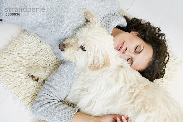 Frau entspannt sich mit Hund auf dem Teppich