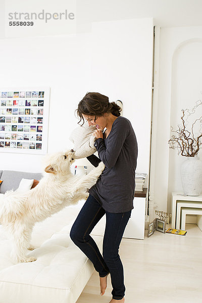 Frau spielt mit Hund im Wohnzimmer