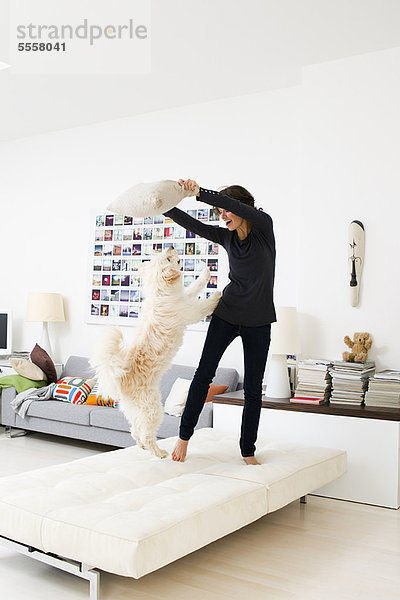 Frau spielt mit Hund im Wohnzimmer