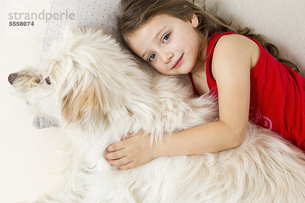 Mädchen entspannt im Bett mit Hund