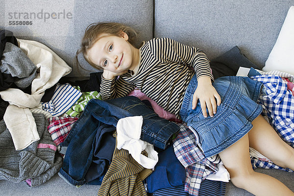 Lächelndes Mädchen  das auf einem Wäschestapel liegt.