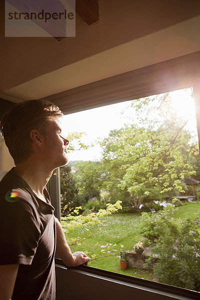 Mann bewundert die Landschaft vom Fenster aus