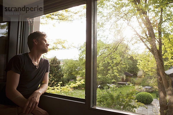 Mann bewundert die Landschaft vom Fenster aus