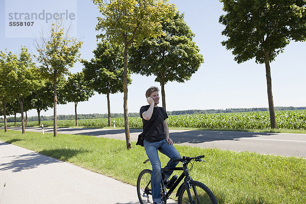 Mann im Gespräch auf dem Handy auf dem Fahrrad